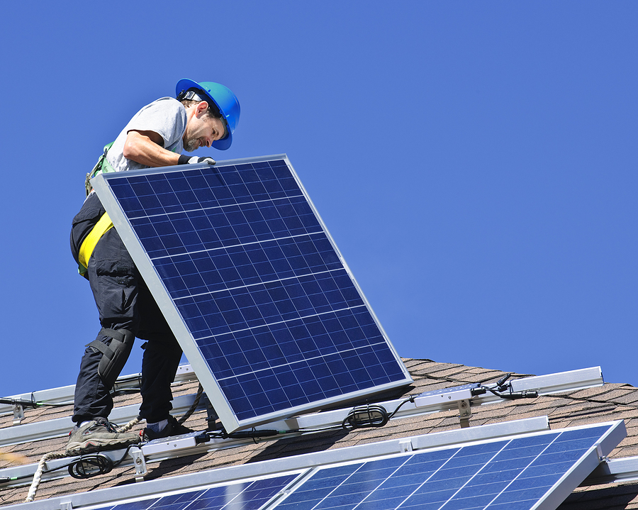 Worker installing solar panels on the roof